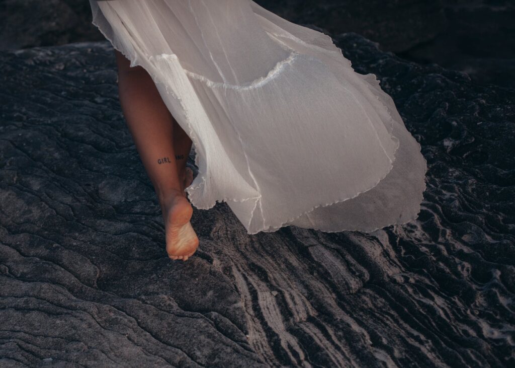 woman wearing white dress walking on sand